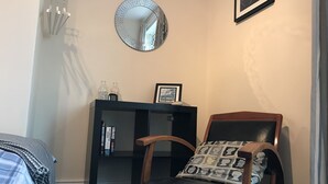 Ein Zimmer mit einem Holzbett, einem schwarzen Bücherregal, einem runden Spiegel und einem gerahmten Bild an der Wand.