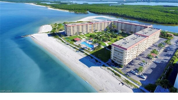 An aerial view of a beachfront hotel with multiple buildings, a swimming pool, and a parking area. - A Little Slice of Paradise !! (Bonita Springs)