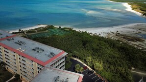 A high-rise hotel overlooking a beach with a tennis court and a parking lot. - A Little Slice of Paradise !! (Bonita Springs)