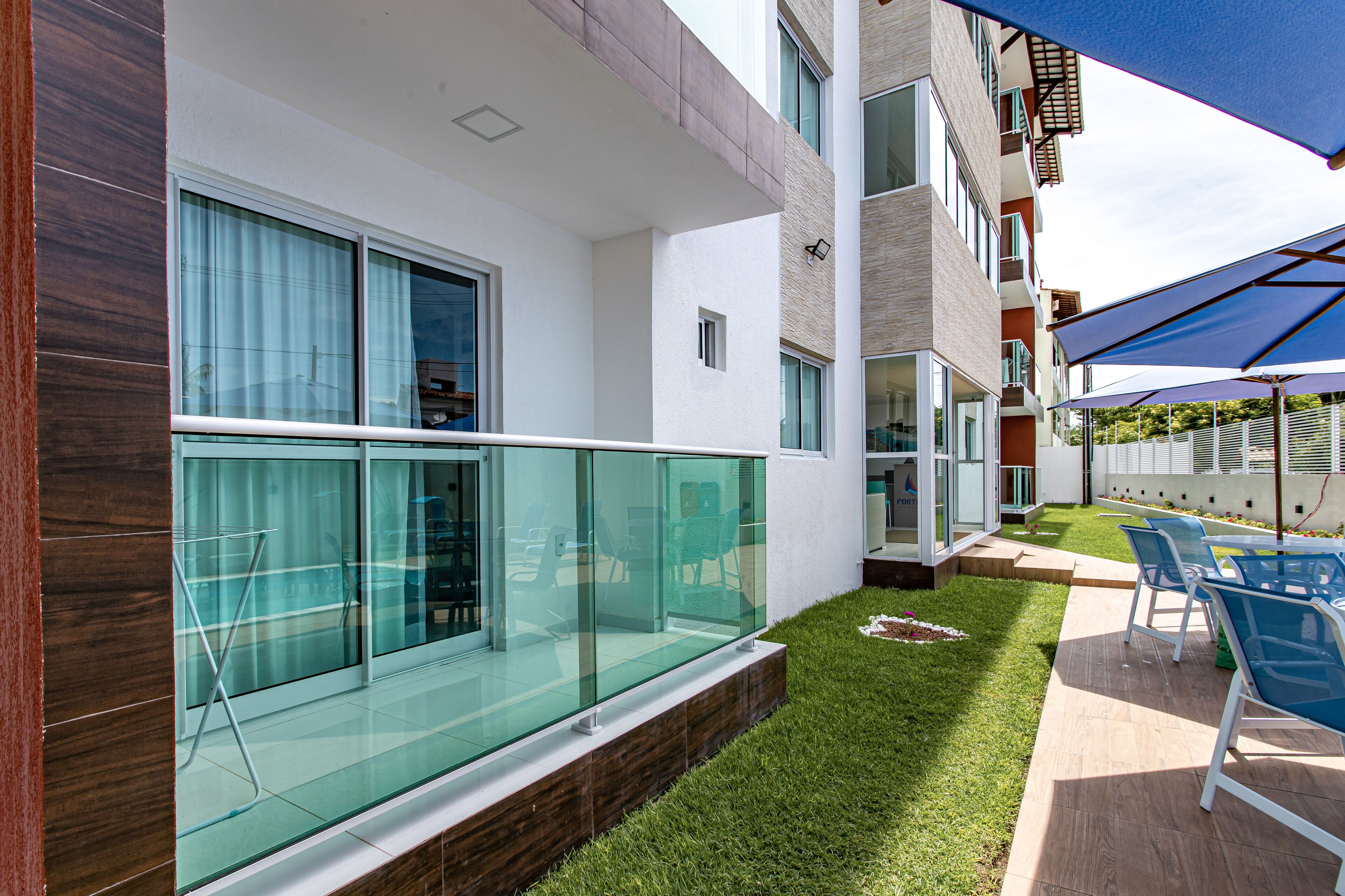 A modern building with a glass balcony, outdoor seating, and a well-maintained lawn.
