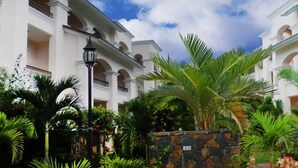 Un hôtel aux murs extérieurs blancs, doté de nombreux balcons et agrémenté d’une végétation tropicale luxuriante.