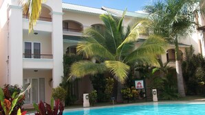 Un hôtel doté d’une piscine, de palmiers et d’un panneau indiquant une profondeur de 1,8 mètre.