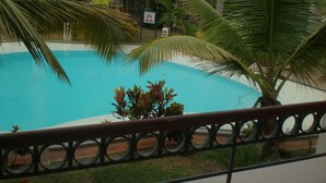 Une piscine entourée de palmiers et un bâtiment en arrière-plan.