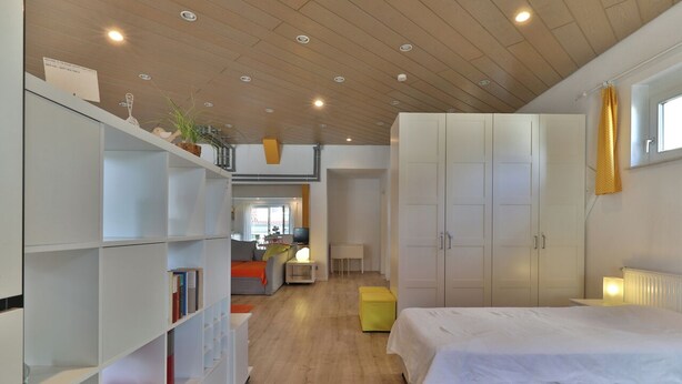 A modern bedroom with a large bed, white wardrobe, and a wooden ceiling. - Nürtingen: spacious loft-style apartment between orchards and Neckar (Nürtingen)