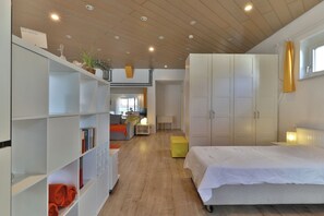 Un dormitorio moderno con una cama grande, un armario blanco y un techo de madera.