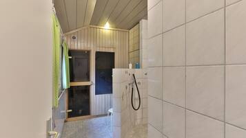 Ein schmales Badezimmer mit Dusche, gefliesten Wänden und Holzboden.