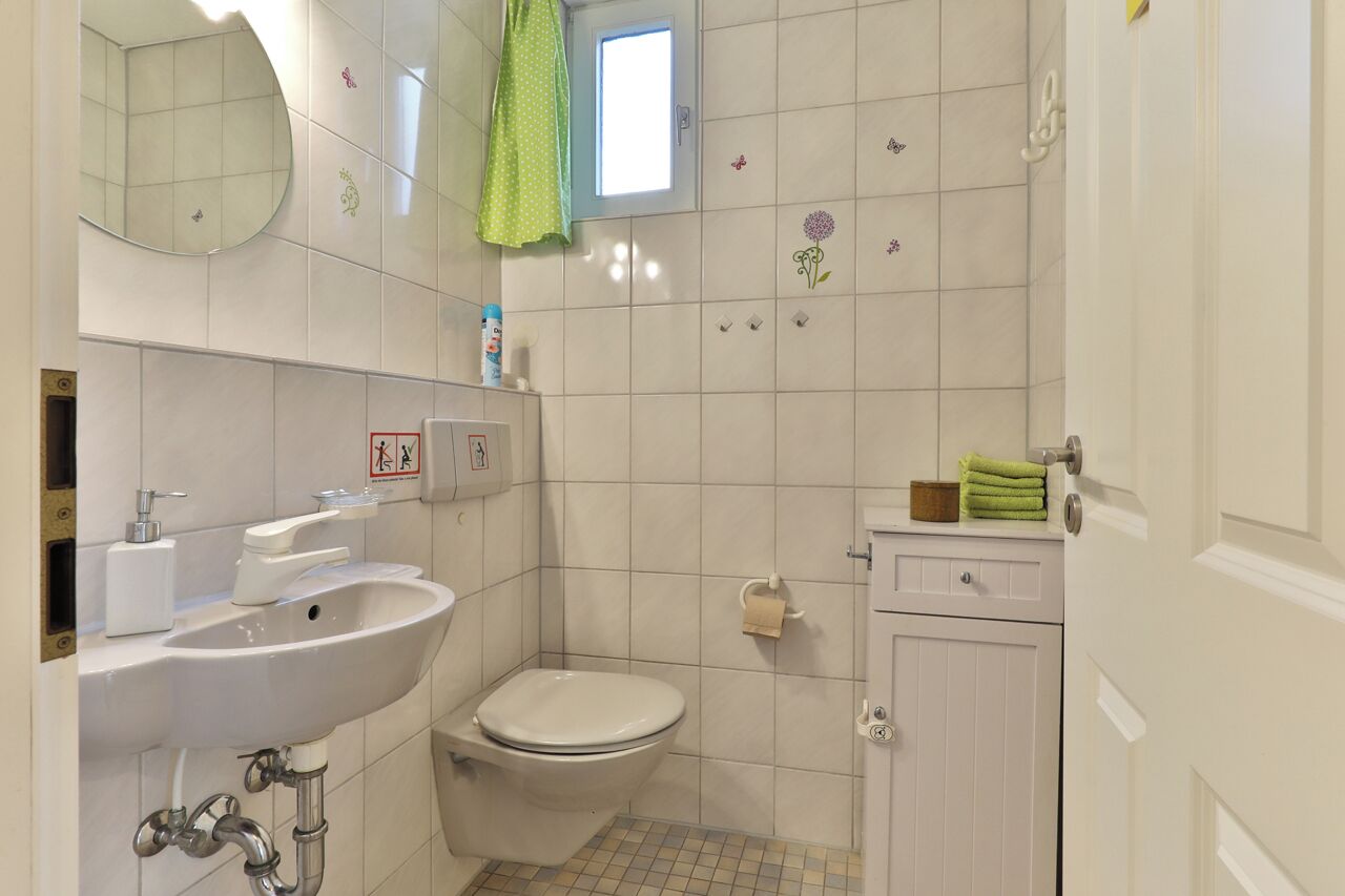 A small, clean bathroom with a sink, toilet, and a mirror.