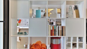 A modern kitchen with white cabinetry, a blue cylindrical object, and neatly arranged books and kitchen utensils. - Nürtingen: spacious loft-style apartment between orchards and Neckar (Nürtingen)