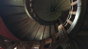 Una escalera de caracol con columna central y escalones de madera.