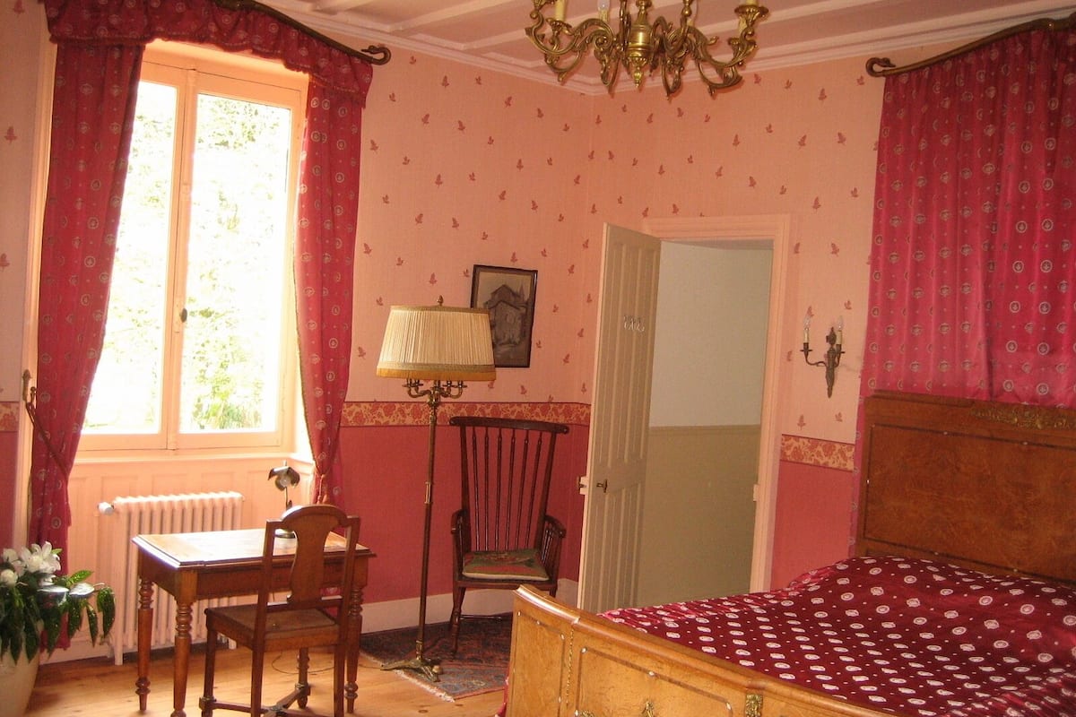 Une pièce comprenant un lit, une table, des chaises, une lampe et un radiateur.