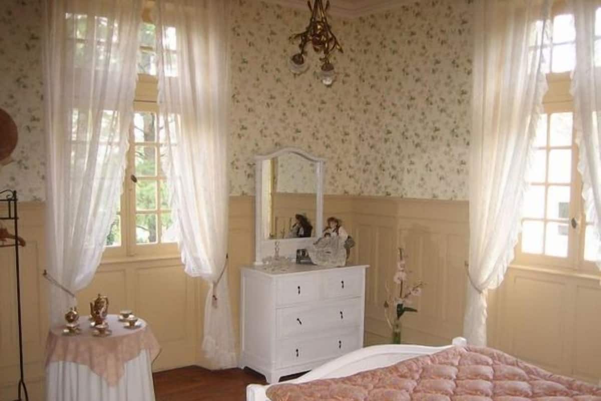 Une chambre à coucher avec un lit, une commode, un miroir et une petite table avec une lampe.