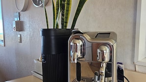 Eine Breville Espressomaschine steht auf einer Küchenarbeitsplatte, neben ihr ein Blumentopf.