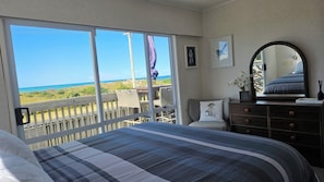 Relax in this serene space with a large bed, dresser, and chair, offering a stunning ocean view.