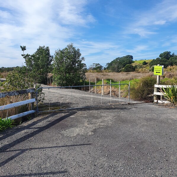 A gravel path leading to a pedestrian access cycleway, surrounded by natural vegetation and a clear sky.