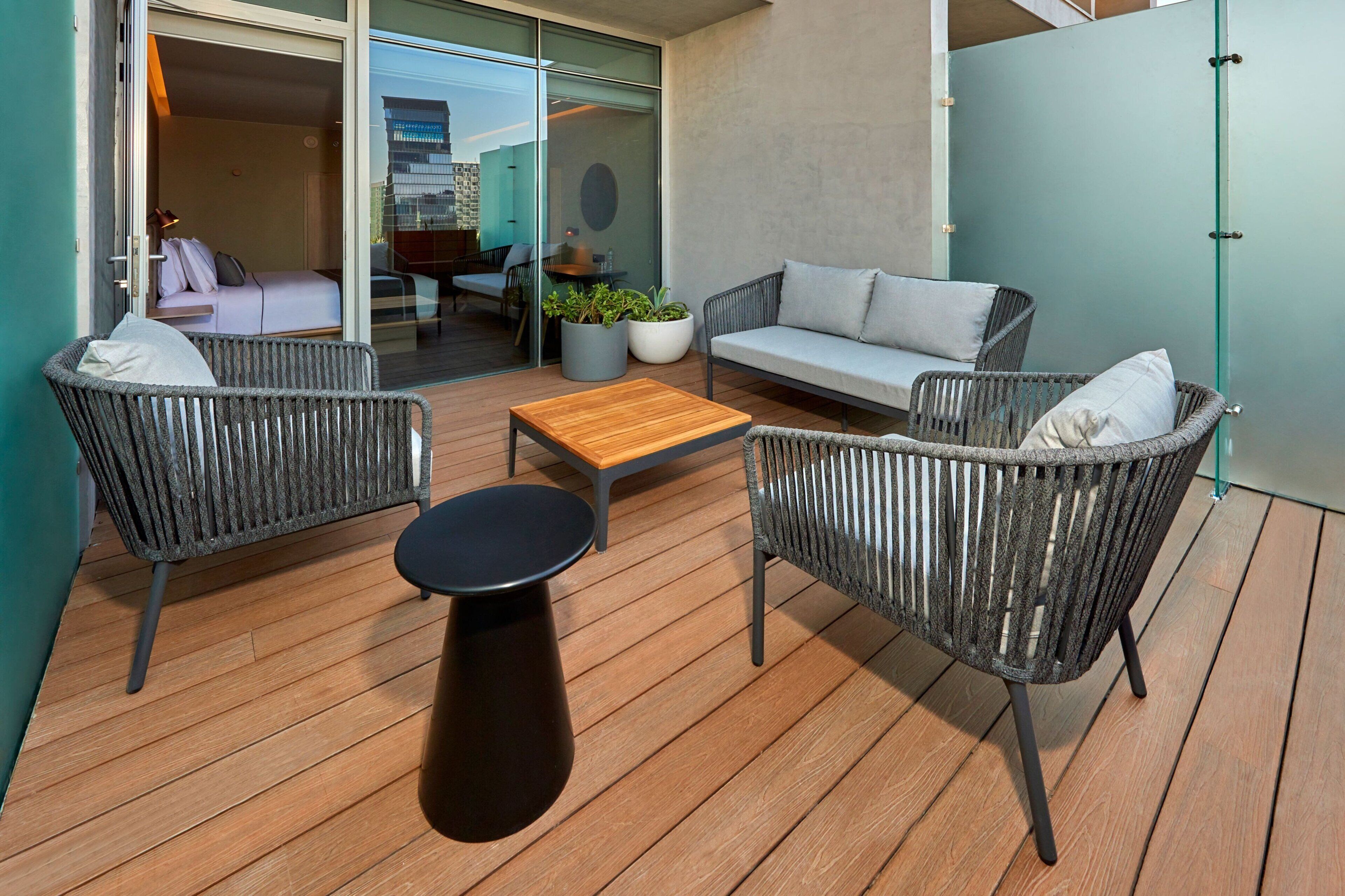 A modern outdoor seating area with wicker furniture, a wooden table, and a potted plant.