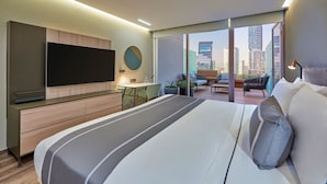 A modern hotel room with a large bed, a flat-screen TV, a desk, and a balcony with city views. - City Express Plus by Marriott Guadalajara Providencia (Guadalajara)