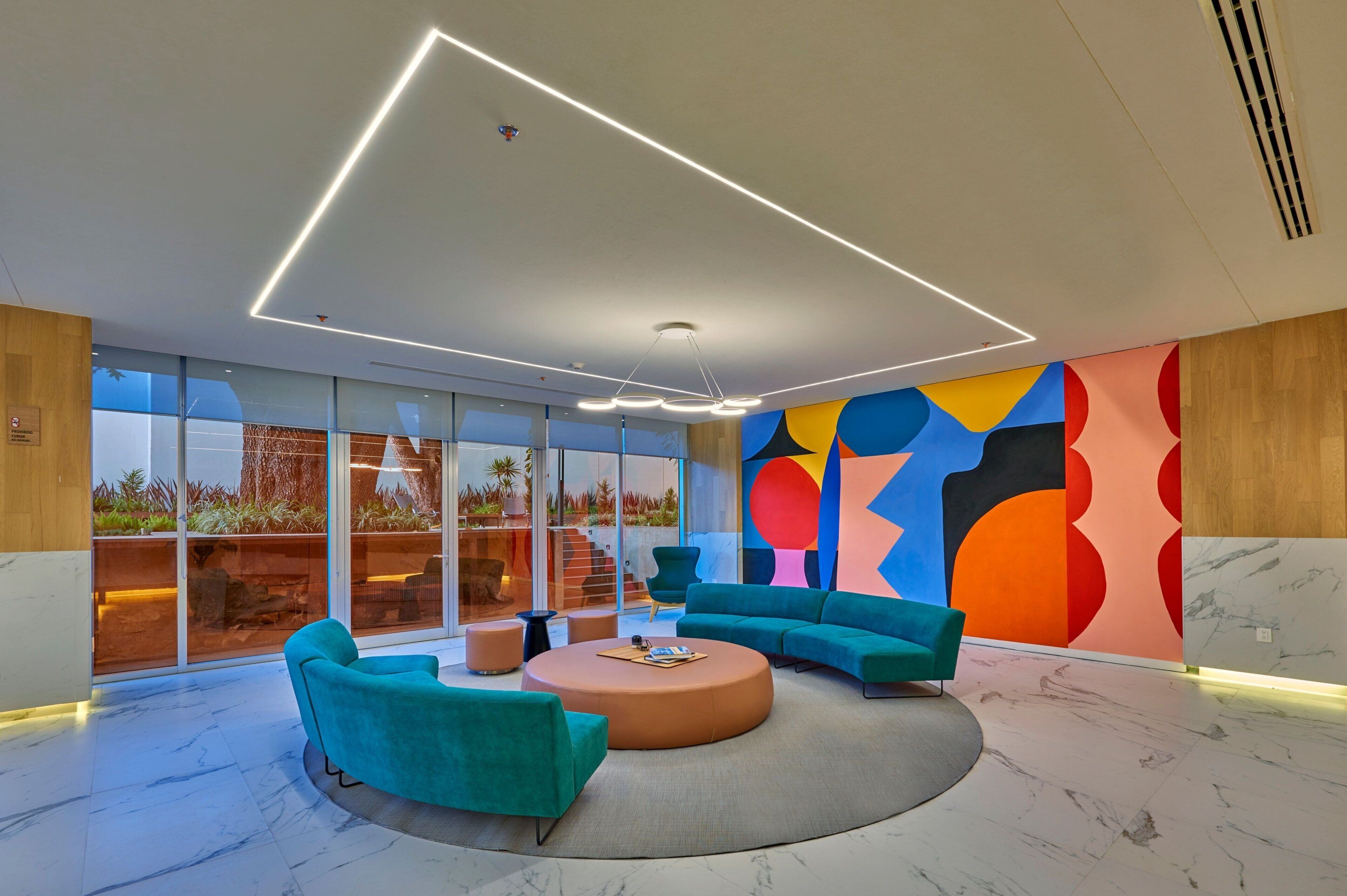 A modern interior with a round seating area, large windows, and a colorful abstract wall.