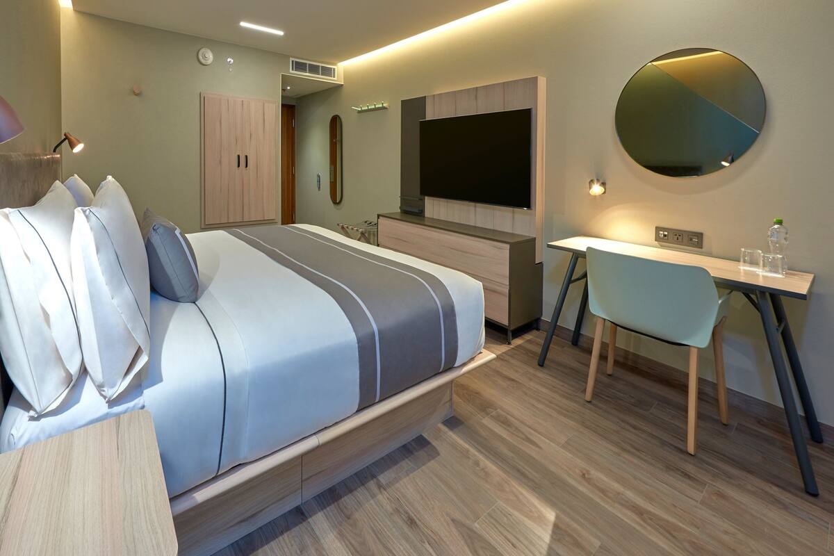 Camera d'albergo moderna con un letto, una scrivania, una sedia, una TV e un armadio.