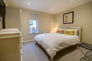 A bedroom with a bed, a window, a lamp, and a wall-mounted picture. - Stonegate Court (York)