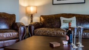 Un canapé en cuir avec un coussin, une table avec une bouteille et des verres, et une lampe fixée au mur.