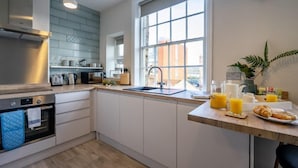 A modern kitchen with white cabinets, a stainless steel oven, and a large window. - Riverside City Loft Apartment (York)