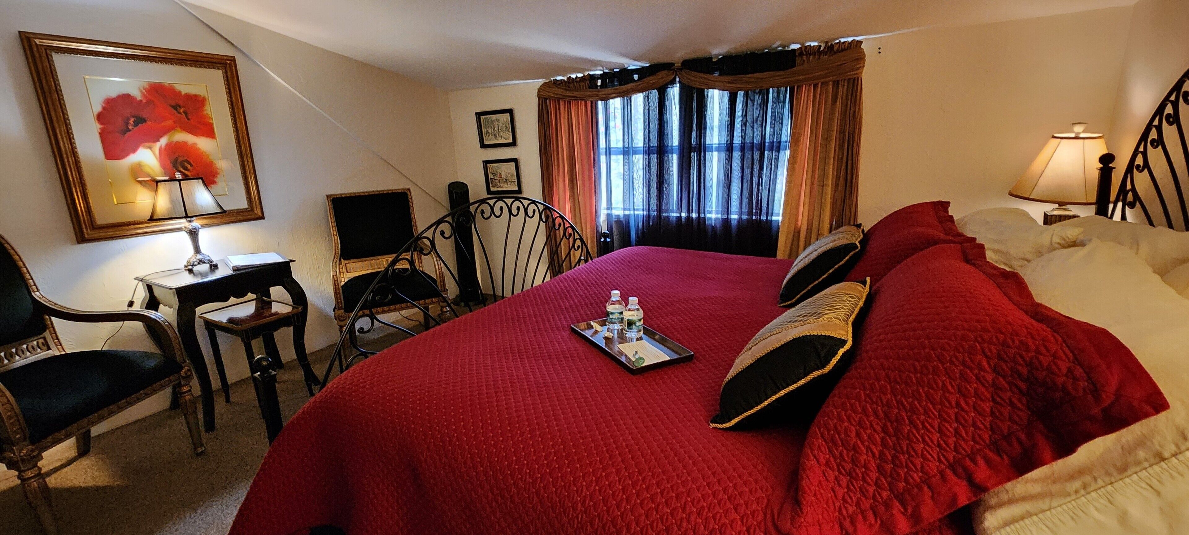 Une chambre d’hôtel avec un grand lit, un bureau avec une chaise, une lampe et un tableau encadré au mur.