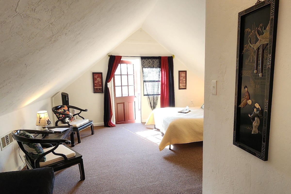 A room with a bed, a desk, and a chair. There are two framed artworks on the wall.