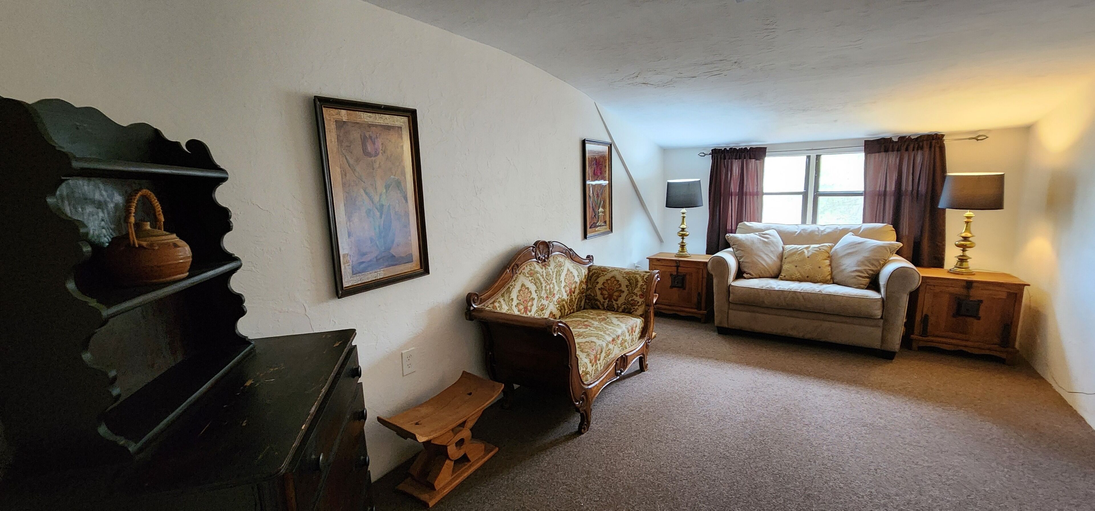 A cozy living room with a sofa, a chair, a wooden cabinet, and a small table.