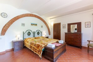 Un dormitorio con cama, cómoda, silla y un arco de madera en el acceso.
