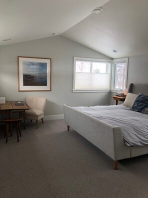 Quarto com cama, escrivaninha, cadeira, janela e quadro na parede.