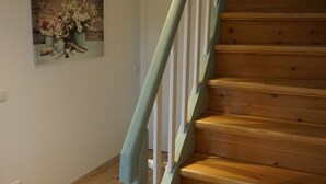 Una escalera de madera con barandilla azul claro que lleva a una puerta blanca.