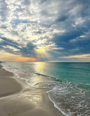 A beach with clear water and a sunset.