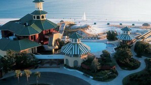 Un resort con varias edificaciones, una piscina y vista al mar.