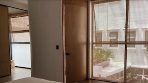 A bedroom with a large bed, a sliding glass door leading to a balcony, and a view of the outside. - Casa Pani (Mexico City)