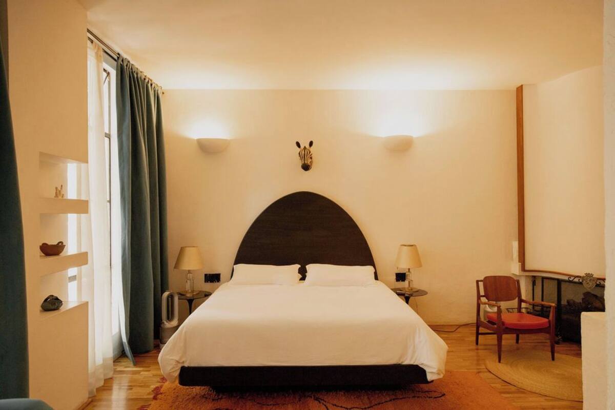 A hotel room with a large bed, two bedside tables, a chair, and a zebra head decoration on the wall.