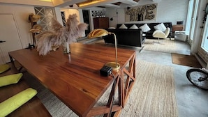 A modern living room with a wooden dining table, a black sofa, and a large abstract painting on the wall. - Casa Pani (Mexico City)