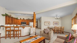 A spacious living area with a kitchen, a dining table, and a sofa. - Blackcomb Greens by Whistler Premier (Whistler)