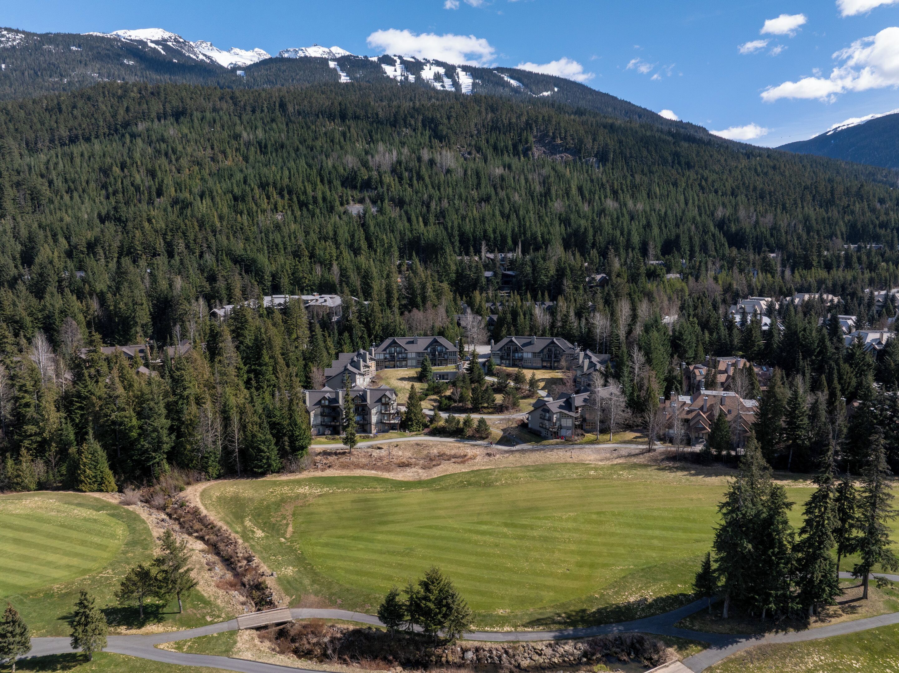 Un complexe hôtelier comprenant plusieurs bâtiments, un terrain de golf et un paysage montagneux en toile de fond.