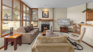 A living room with a fireplace, a sofa, a rocking chair, and a television. - Blackcomb Greens by Whistler Premier (Whistler)