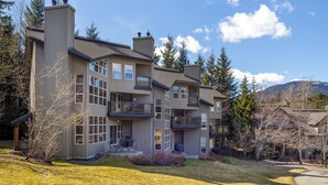 A multi-story house with a balcony, a chimney, and a view of trees and mountains. - Blackcomb Greens by Whistler Premier (Whistler)