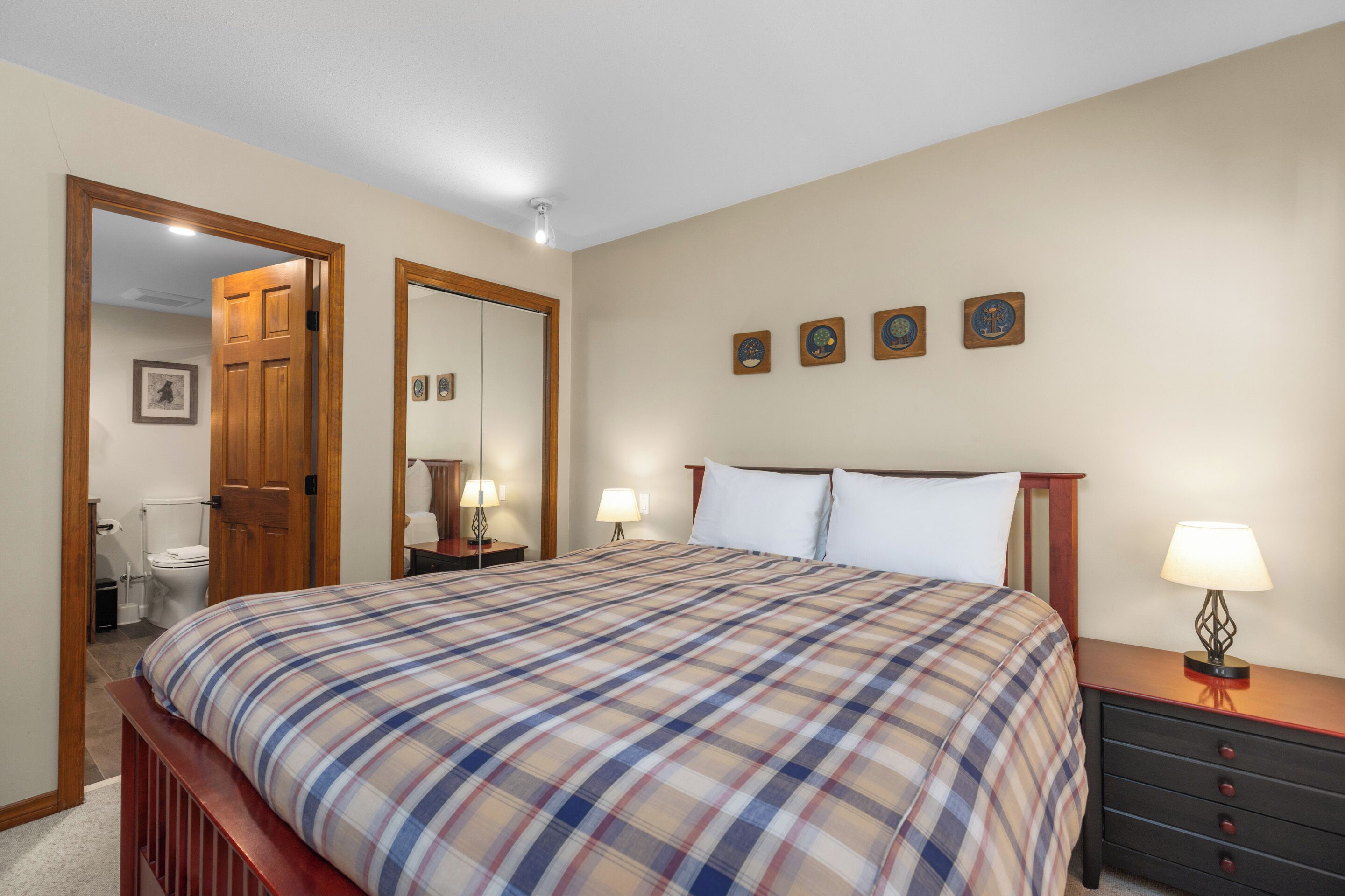 A bedroom with a bed, bedside tables, a mirror, and a door leading to a bathroom.