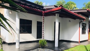 A modern house with a tiled roof, white walls, and a paved courtyard with a small plant. - Asha Villa Weligama (Weligama)