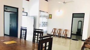 A dining area with a wooden table and chairs, a ceiling fan, and a tiled floor. - Asha Villa Weligama (Weligama)