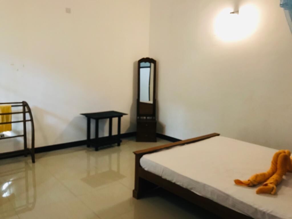 Un dormitorio con cama, espejo, una mesita y una silla.