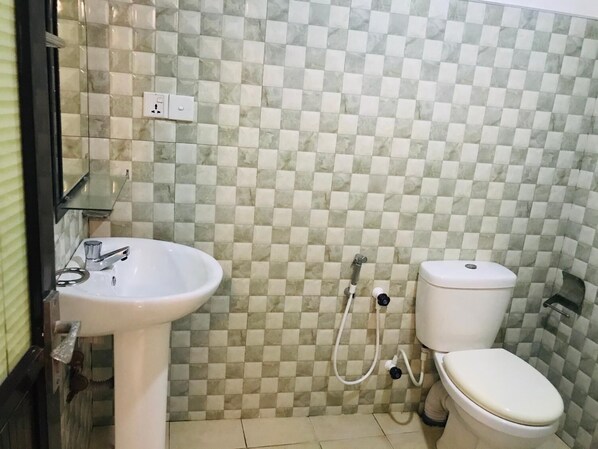 A bathroom with a checkered tile wall, a white sink, and a toilet. - Asha Villa Weligama (Weligama)