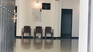 A hallway with a polished floor, three wooden chairs, a blue carpet, a ceiling fan, and a door. - Asha Villa Weligama (Weligama)