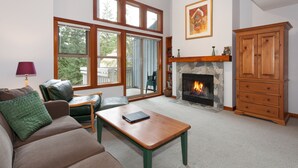 A living room with a fireplace, a sofa, a coffee table, and a wooden cabinet. - Tree Line by Whistler Premier (Whistler)