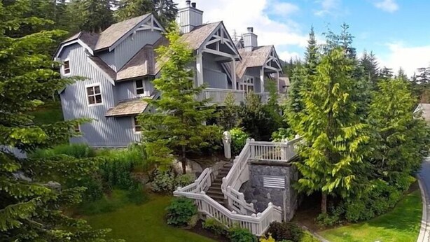 A large, multi-story house with a prominent staircase and lush greenery surrounding it. - Tree Line by Whistler Premier (Whistler)