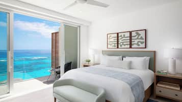 A modern hotel room with a large bed, a ceiling fan, and a view of the ocean.