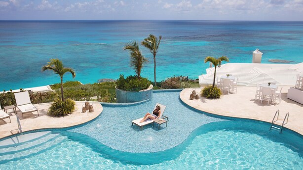 Un espace piscine avec des chaises longues et une personne se relaxant au bord de la piscine.